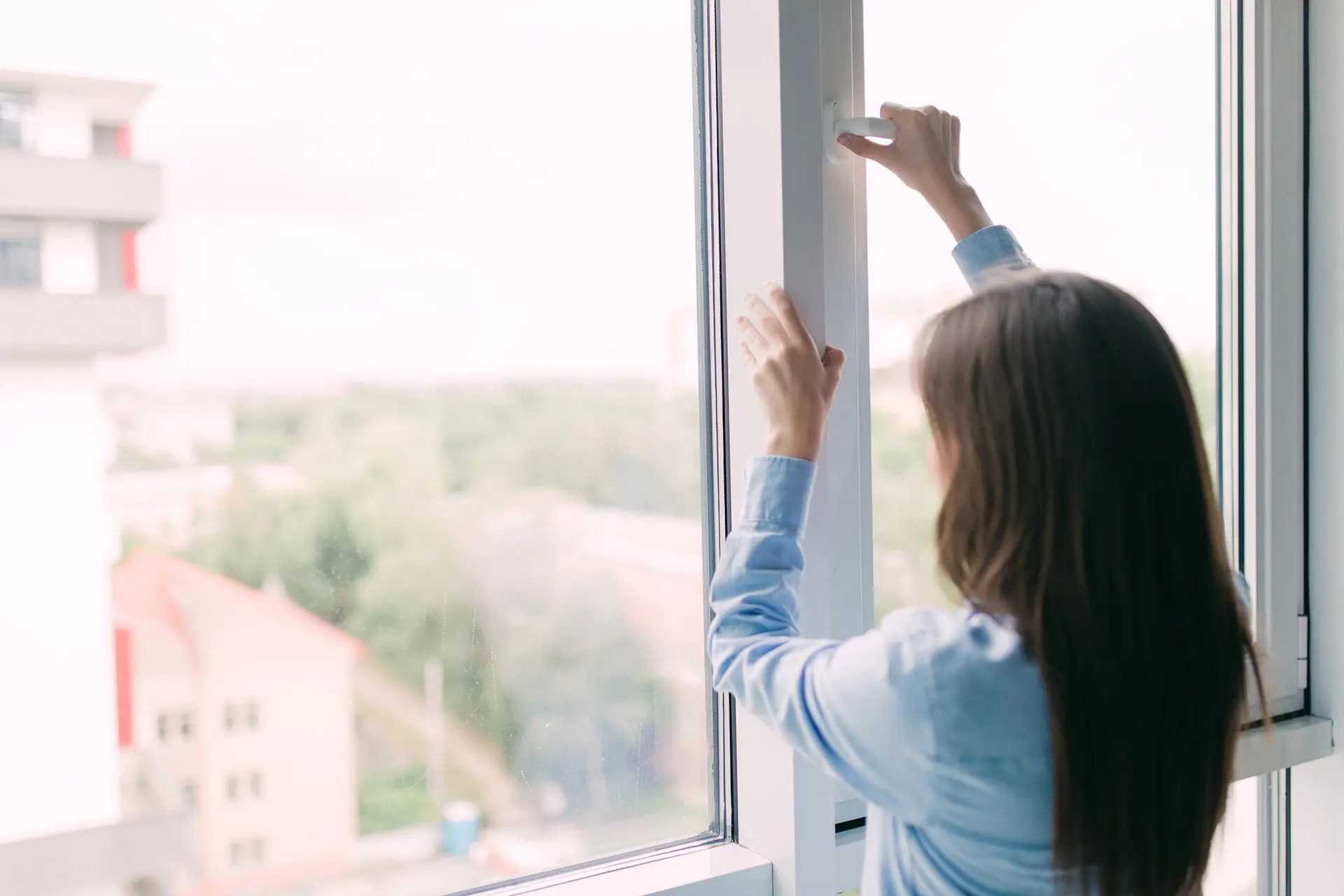 Miten usein puhdistaa kodin ilmanvaihtokanavat Akave - Nainen avaamassa kodin ikkunaa