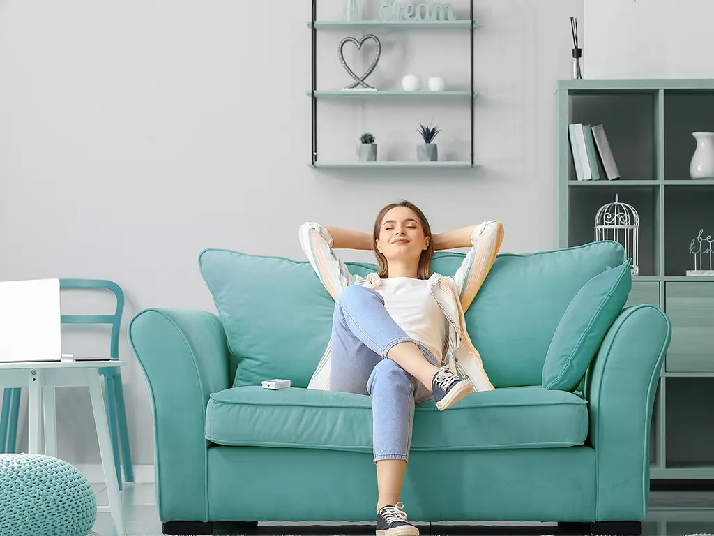 Ilmanvaihtokanavien puhdistus ylläpitää hyvää sisäilmaa Akave - nainen istumassa sohvalla ja rentoutumassa kotona